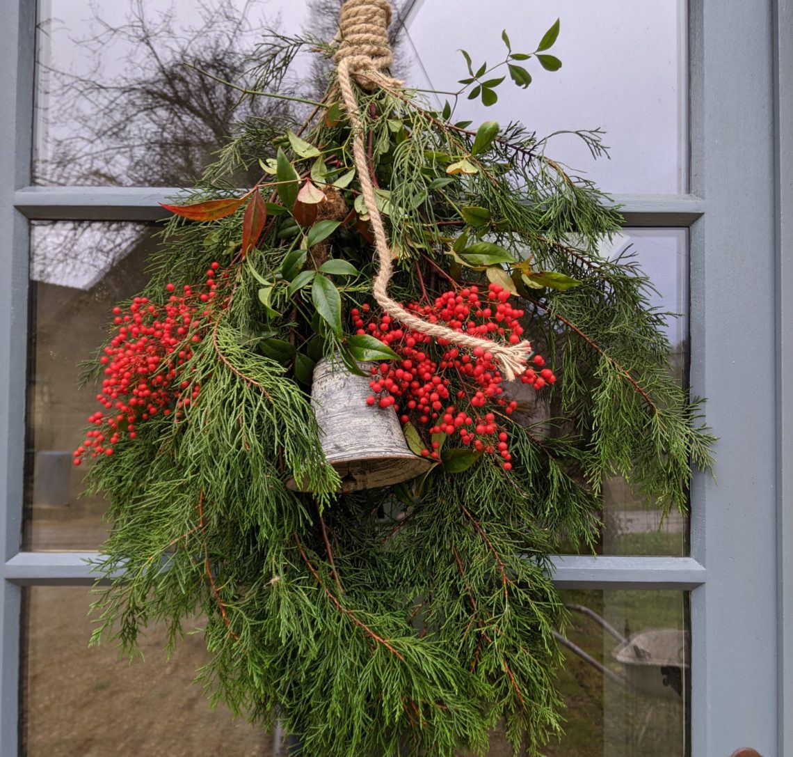 Décoration de Noël sur porte de la maison faite de sapin, corde et cloche